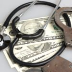Stethoscope, handcuffs and money on gray
