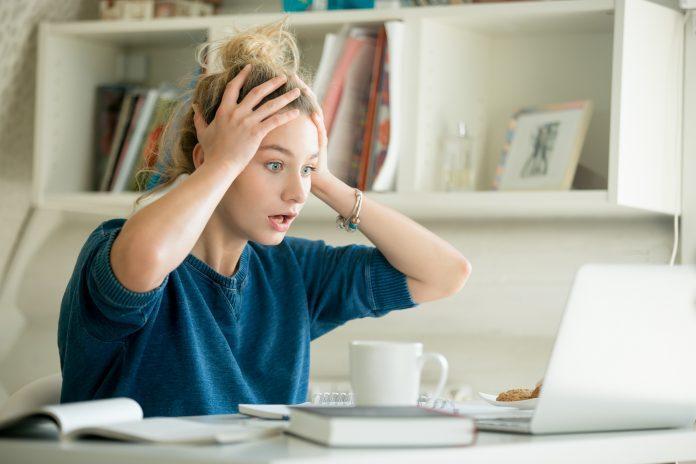 Portrait of an attractive woman at table grabbing her head The latest Facebook kerfulffle
