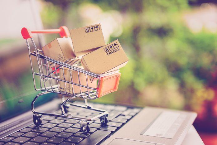 Online shopping and delivery service concept. Paper cartons in a shopping cart on a laptop keyboard, this image implies online shopping that customer order things from retailer sites via the internet. Amazon.com ads