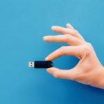 One hand holding pendrive on blue background