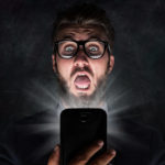 Nerd with glasses is shocked after reading a sms